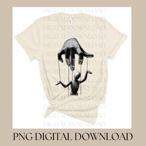 May include: Cream-colored t-shirt featuring a black and white graphic of a hand controlling a puppet. The puppet is a small, stylized figure. The text "PNG DIGITAL DOWNLOAD" is at the bottom of the image.