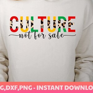 May include: A white sweatshirt with the text "CULTURE not for sale" in red, yellow, green, and black letters with a leopard print pattern.