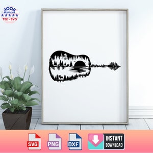 May include: Black and white framed art print featuring a guitar silhouette with a nature scene inside. The design includes trees, a lake, a setting sun, and a deer. The print is displayed on a white wall.