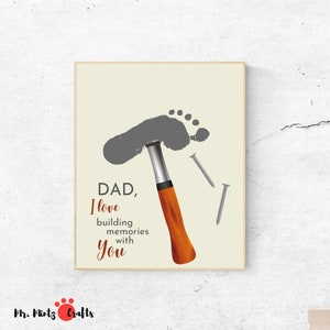 May include: A grey footprint is used to create a hammer with a brown handle. The image includes the text "DAD, I love building memories with you".
