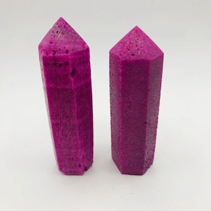 May include: Two purple crystal points with a rough, textured surface.