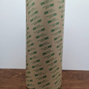 May include: A roll of brown tape with green text that reads "3M 467MP 20051P Adhesive".