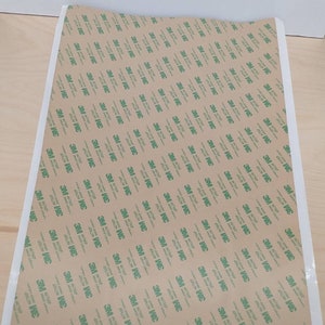 May include: A roll of brown adhesive tape with a white border and a repeating pattern of green 3M logos.