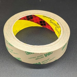 Puede incluir: Un rollo de cinta adhesiva de doble cara Scotch 3M con una etiqueta verde y blanca que dice "467MP 200MP Adhesive".