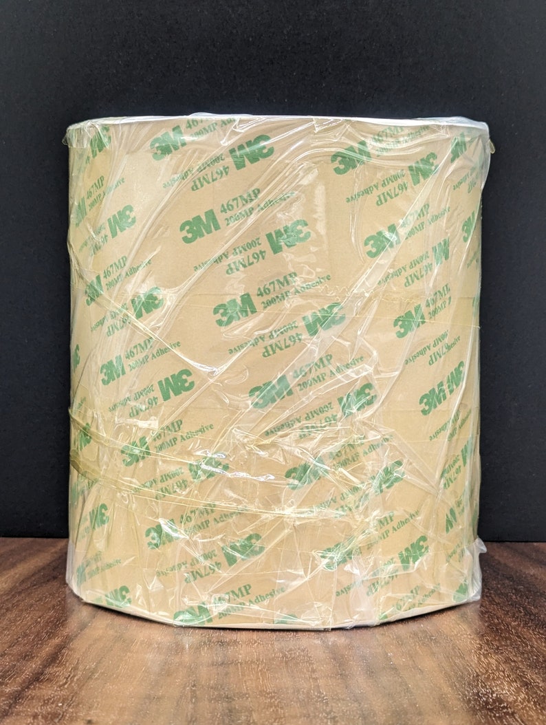 May include: A roll of brown 3M 467MP 200MP Adhesive tape wrapped in clear plastic. The tape is labelled with the text "3M 467MP 200MP Adhesive".