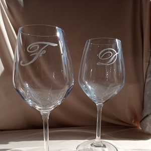 Może przedstawiać: Dwa przezroczyste szklane kieliszki do wina z wygrawerowanymi inicjałami "F" i "D" na przodzie każdego kieliszka.