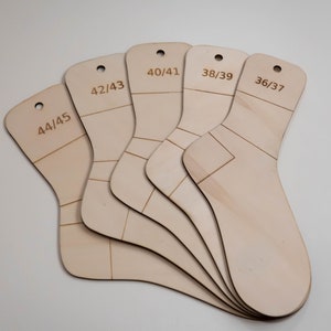 Könnte beinhalten: Fünf hölzerne Socken-Größenleitfäden, jeder mit einer anderen Größe darauf markiert. Die Größen sind 44/45, 42/43, 40/41, 38/39 und 36/37.