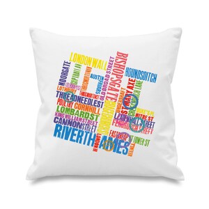May include: White square pillow with a colorful design featuring London street names. The text is arranged in a stylized, abstract shape, with names like "London Wall" and "River Thames" in various colors.