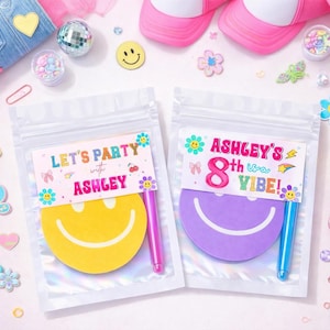 May include: Two clear cellophane bags with colorful party favors. One bag has a yellow smiley face and the text "LET'S PARTY with ASHLEY". The other has a purple smiley face and the text "ASHLEY'S 8th VIBE!".