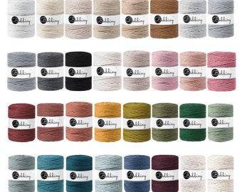 Könnte beinhalten: Eine Sammlung von 28 Spulen aus natürlichem Baumwollseil in verschiedenen Farben, darunter Beige, Grau, Schwarz, Braun, Rosa, Grün, Blau und Rot. Jede Spule ist mit dem Wort "Bobbiny" gekennzeichnet.