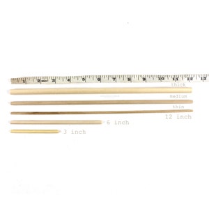 May include: Four wooden dowels of varying lengths and thicknesses. The dowels are arranged from longest to shortest. The longest dowel is 12 inches long and labeled "thick". The next dowel is 12 inches long and labeled "medium". The third dowel is 6 inches long and the shortest dowel is 3 inches long.