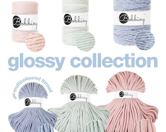 May include: Six spools of cotton cord in various colors, including pink, light blue, and mint green. The cord is textured and has a subtle shimmer. The spools are labeled "Bobbiny" and "the knot shop."