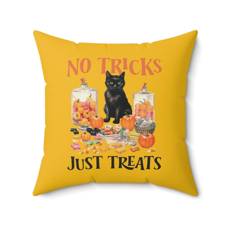 Puede incluir: Un coj&iacute;n cuadrado amarillo con un dise&ntilde;o de Halloween. Presenta un gato negro, calabazas y tarros de caramelos. El texto "NO TRICKS JUST TREATS" est&aacute; impreso en naranja.