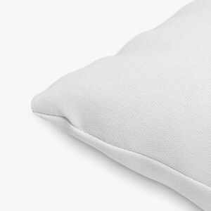 May include: Close-up of a white pillow cover with a smooth, textured surface. The fabric is soft and appears to be made of cotton.