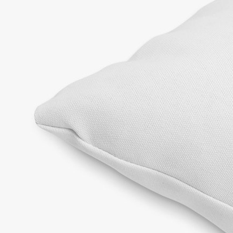 May include: Close-up of a white pillow cover with a smooth, textured surface. The fabric is soft and appears to be made of cotton.