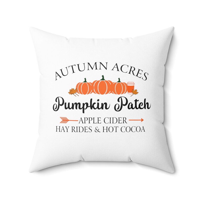 May include: White throw pillow with the text "Autumn Acres Pumpkin Patch" in black lettering.  The text is surrounded by three orange pumpkins and a cup of coffee.  Below the pumpkins is the text "Apple Cider Hay Rides & Hot Cocoa" in black lettering.