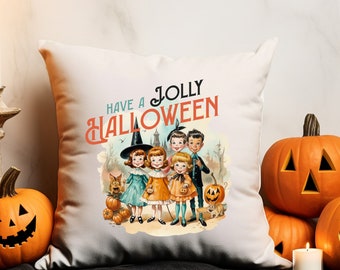 May include: A white throw pillow featuring a vintage-style illustration of five children in Halloween costumes, including a witch, with the text "HAVE A JOLLY HALLOWEEN" printed in teal and orange above the group, surrounded by pumpkins.