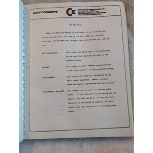 Pu&ograve; includere: Pagina di libro aperta con testo sulle funzioni PET e ASCII. Il logo Commodore &egrave; in alto a sinistra. Il testo spiega funzioni come ASC, CHRS, VAL e STRS, con esempi nella programmazione BASIC.