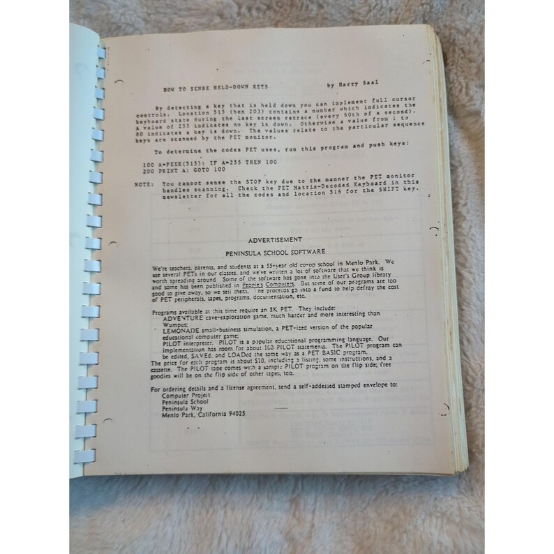 Pu&ograve; includere: Libro aperto con testo manoscritto e stampato sulla programmazione informatica. Il testo include istruzioni su come utilizzare un computer PET e una pubblicit&agrave; per Peninsula School Software.