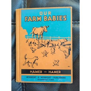 May include: A vintage book cover with an orange background and blue text that reads "Our Farm Babies" by Hamer - Hamer. The cover features a black and white illustration of a cow, pigs, and chicks on a farm.