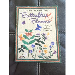 May include: A book titled "Butterflies & Blooms" by Carol Armstrong. The cover features a colorful illustration of butterflies and flowers, with the text "Designs for Appliqué & Quilting".