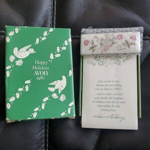 Puede incluir: Una caja verde con una paloma blanca y el texto "Happy Holidays AVON 1980". Una tarjeta blanca con un diseño floral y el texto "Just a note to say thanks for everything you've done in 1980 - and to wish you and your family the happiest of holidays and all my own best wishes for the coming year.  William F. Chaney"