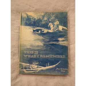 May include: A blue and white book cover with the title "This is What I Remember" and the words "Susan  Selden Bury editions" at the bottom. The cover features a watercolor illustration of a person on horseback riding through a river.