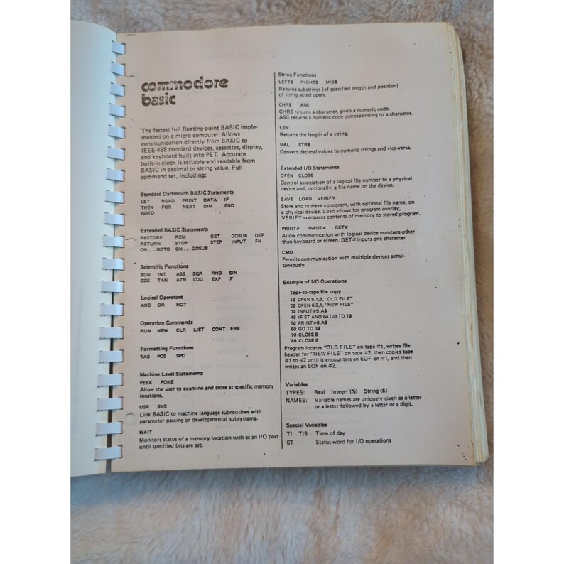 Pu&ograve; includere: Pagina di libro aperta con testo sul linguaggio di programmazione Commodore BASIC. Il testo include comandi, funzioni ed esempi per la programmazione di microcomputer. La pagina &egrave; ingiallita.