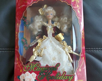 May include: A red box with a white doll wearing a white and gold dress and a red and gold jacket. The doll is holding a gold gift box. The box has the words "Magical Holiday Collection" on it.