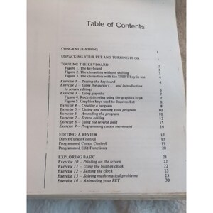 Pu&ograve; includere: Una pagina di un vecchio manuale di computer, che mostra un sommario. Il testo include sezioni sull'uso della tastiera, la grafica e le basi della programmazione. La pagina &egrave; bianca con testo nero, e il titolo "Table of Contents" &egrave; in alto.
