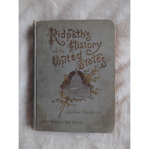 May include: A vintage book titled "Ridpath's History of the United States" with a gold-embossed image of the US Capitol building on the cover. The book is bound in a light blue fabric with gold lettering.
