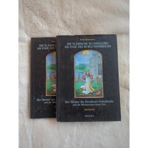Può includere: Due libri con copertina rigida nera. Il titolo sulla copertina recita "DIE FLÄMISCHE BUCHMALEREI AM ENDE DES BURGUNDERREICHS" e "Der Meister des Dresdener Gebetbuchs". Le copertine dei libri presentano un'illustrazione colorata di una scena religiosa.