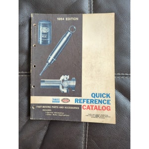 May include: A vintage 1964 edition Ford Rotunda Quick Reference Catalog. The cover features illustrations of automotive parts, including a filter, a tool, and a drive shaft. The catalog is for fast-moving parts and accessories.