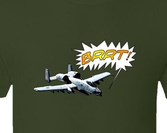 May include: A green t-shirt with a cartoon image of a military aircraft flying with a speech bubble that says "BRRT!"