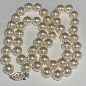 May include: A strand of lustrous, off-white pearls. The necklace features a delicate silver clasp with an ornate design. The pearls are round and evenly sized, creating a classic and elegant look. The necklace is suitable for formal occasions.