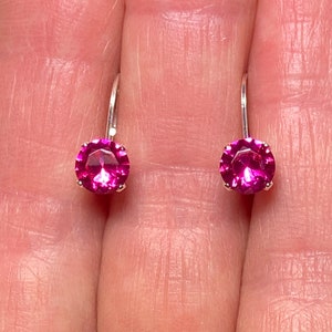 May include: A pair of silver earrings with pink round gemstones.