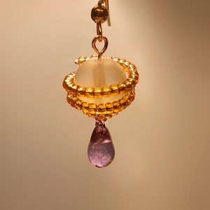 May include: Gold beaded earrings with a clear glass bead and a dangling purple teardrop bead.