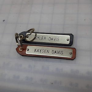 May include: Two leather keychains with metal plates engraved with the names "KYLER DAVIS" and "KAYSEN DAVIS".