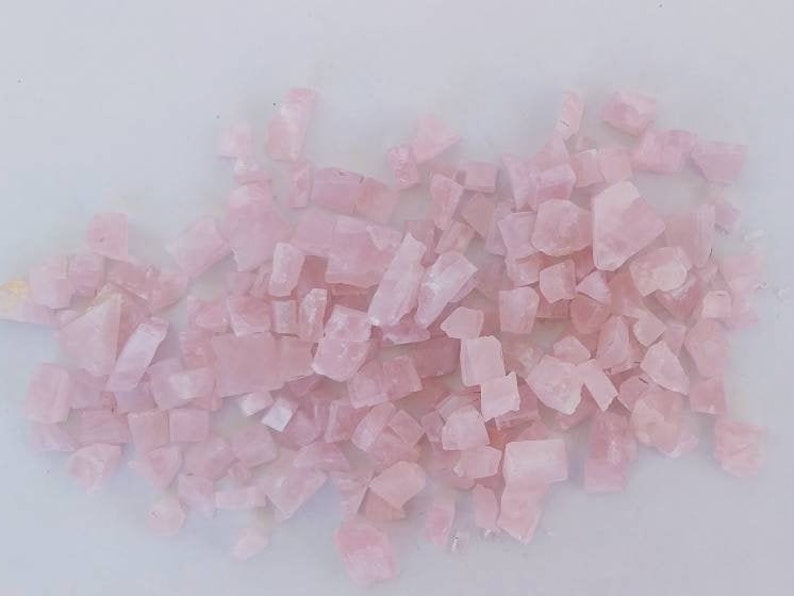 May include: A large pile of pink rose quartz crystals. The crystals are various sizes and shapes, and they are all a light pink color.
