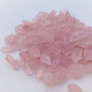 May include: A pile of small, light pink, irregularly shaped crystal chips.