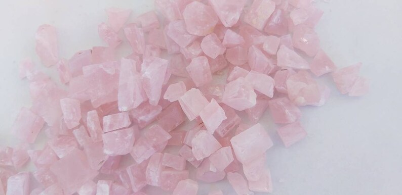 May include: A large pile of pink rose quartz crystals. The crystals are various shapes and sizes.