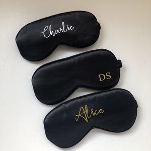 May include: Three black satin sleep masks with personalised embroidery. The top mask says "Charlie" in white lettering. The middle mask says "DS" in gold lettering. The bottom mask says "Alice" in gold lettering.