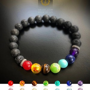 May include: A black lava rock bracelet with seven chakra beads in the colors of the rainbow. The beads are red, orange, yellow, green, turquoise, blue, and purple. The bracelet is accented with silver beads. ZENITUDE LIVING HEALTH JOY LIFE is written on the background.