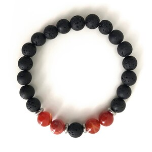Op de afbeelding: Een armband van zwarte lavasteen en carneol kralen. De armband heeft in totaal 19 kralen, waarvan 15 zwarte lavasteen kralen en 4 carneol kralen.