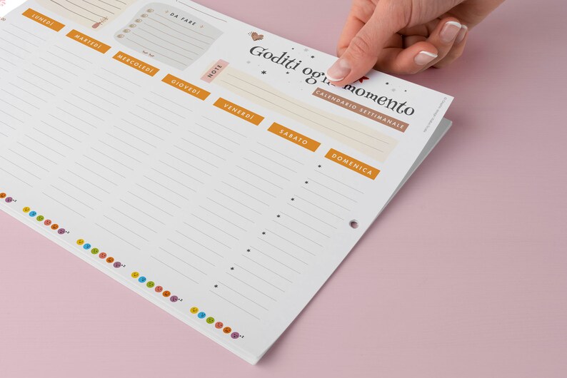 May include: A weekly planner with a white background and orange and beige accents. The planner has sections for each day of the week, notes, and a to-do list. The top of the planner has the text "Goditi ogni momento" and "Calendario Settimanale".