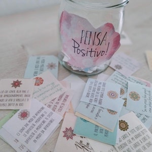 Puede incluir: Un tarro de vidrio con un dise&ntilde;o de acuarela rosa y blanco que dice "PENSA Positivo!" El tarro est&aacute; lleno de peque&ntilde;as tarjetas con mensajes inspiradores escritos en italiano.
