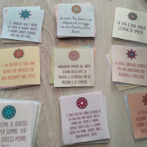 Puede incluir: Una colecci&oacute;n de tarjetas coloridas con citas inspiradoras en italiano. Cada tarjeta presenta un dise&ntilde;o de mandala decorativo en tonos de azul, rojo y verde. Las citas son sobre el coraje, la vida y la felicidad.