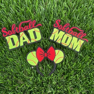 Puede incluir: Tres parches bordados con temática de softbol. Los parches son verdes y negros con costuras rojas. Los parches dicen "Softball Dad", "Softball Mom" y presentan una pelota de softbol con un lazo rojo.
