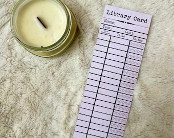 May include: A pink and white library card with the text "Library Card" at the top. The card has spaces to fill in the name, year, goal, title, and rating of books read. The card has a five-star rating system.