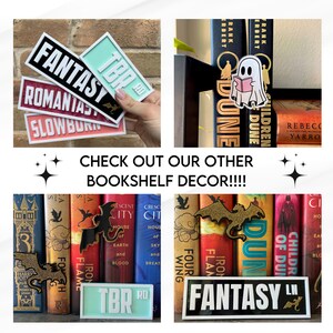Puede incluir: Una estanter&iacute;a decorada con sujetalibros y pegatinas con tem&aacute;tica de fantas&iacute;a. Los sujetalibros son un drag&oacute;n negro, un drag&oacute;n dorado y un fantasma. Las pegatinas dicen "Fantasy", "TBR", "Romaniast" y "Slowburn".